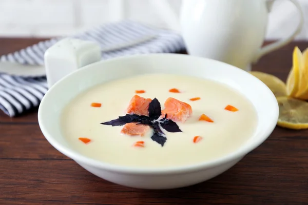 Delicious salmon cream soup in white plate on wooden table, close up — Stock Photo, Image