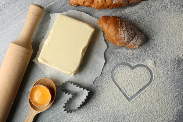 Heart of flour, croissant and  wooden kitchen utensils on gray background — Stock Photo, Image