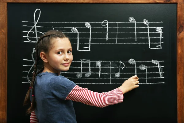 Menina escrevendo em notas musicais quadro-negro — Fotografia de Stock