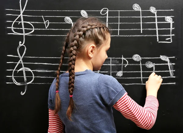 Menina escrevendo em notas musicais quadro-negro — Fotografia de Stock