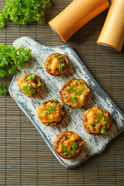 Stuffed mushrooms on wooden board, on table background — Stock Photo, Image