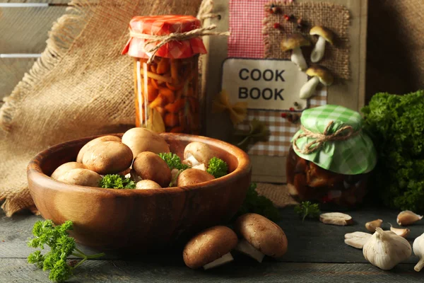 Funghi in ciotola di legno e funghi marinati in vaso su superficie di legno — Foto Stock