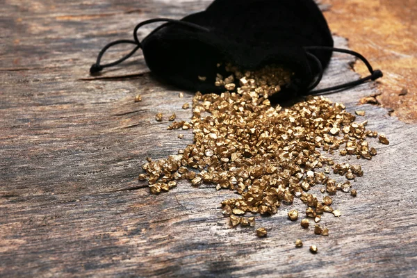 Une pochette avec des grains de pépites d'or éparpillés — Photo