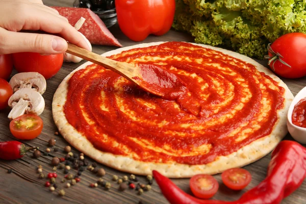 Degen basen med ketchup och ingredienser för pizza — Stockfoto