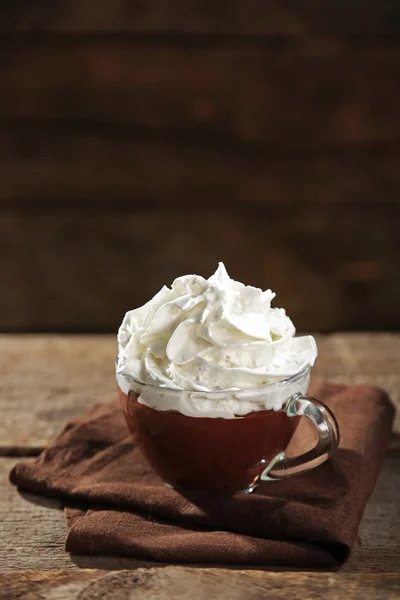 Chocolate quente com chantilly na caneca no fundo de madeira — Fotografia de Stock