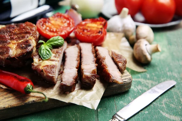 Filet de bœuf rôti et légumes sur planche à découper, sur fond bois — Photo