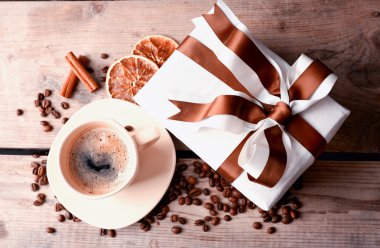 Güzel hediye, fincan kahve ve kahve taneleri ahşap arka plan üzerinde