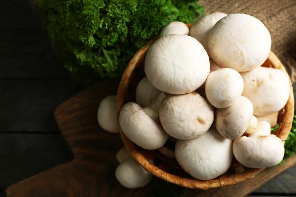 Champiñones en cesta sobre superficie de madera — Foto de Stock