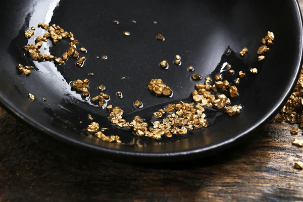 Gold nugget grains, on black plate, close-up — Stock Photo, Image
