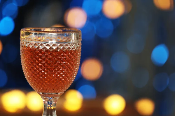Un bicchiere di vino rosa su sfondo sfocato illuminato — Foto Stock