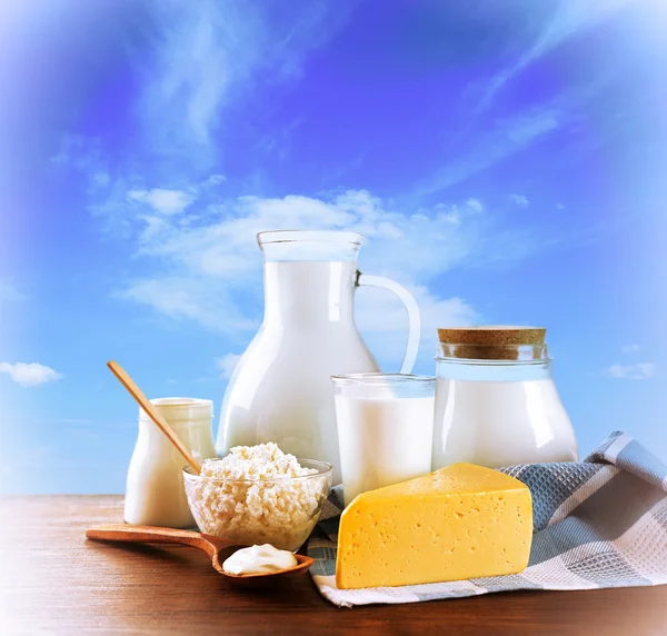 Productos lácteos sobre mesa de madera sobre fondo celeste — Foto de Stock