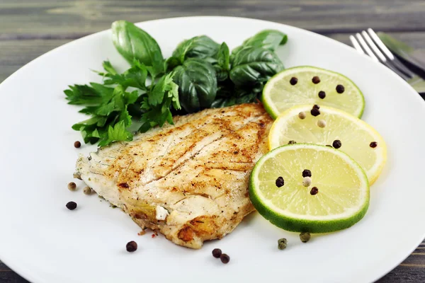 Schotel van visfilet met Groenen en kalk op tafel close-up — Stockfoto