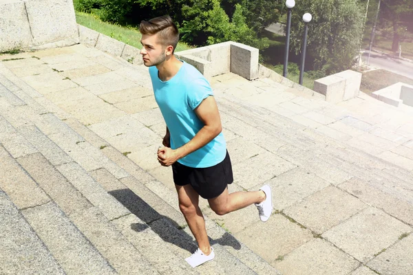 Young man jogging at stairs outdoors — Stock Photo, Image