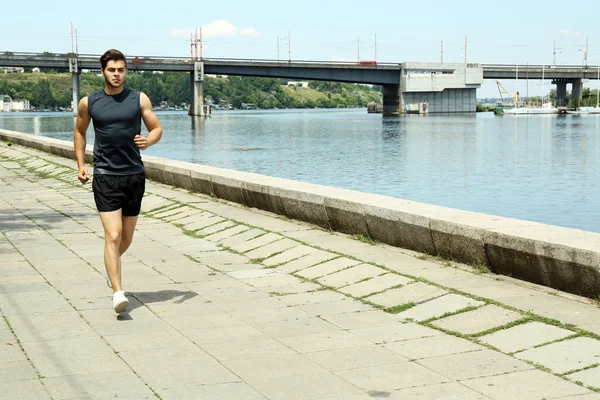 Young man jogging near river — Stock Photo, Image