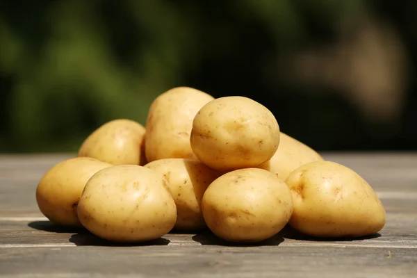 Pilha de batatas novas na mesa de madeira no fundo desfocado natural — Fotografia de Stock