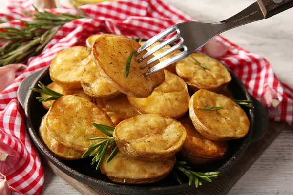 Batata assada deliciosa com alecrim na frigideira na mesa close-up — Fotografia de Stock