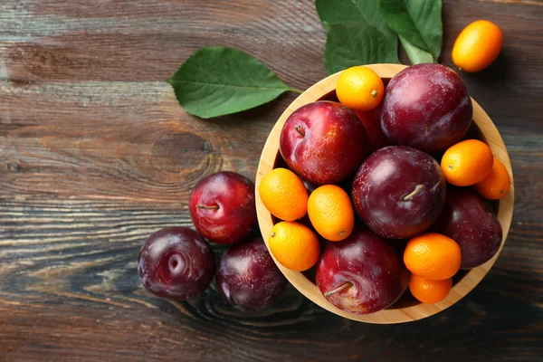 Ripe plums on wooden table, top view — Stock Photo, Image