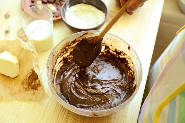 Женщина готовит тесто для шоколадного пирога на столе. — стоковое фото