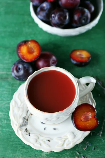 Läckra plommon juice med frukter på träbord nära håll — Stockfoto