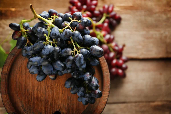 Старый винный бочка и виноград на деревянном фоне — стоковое фото