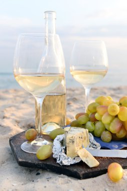 Beyaz şarap ve üzüm kum plajındaki romantik kompozisyon