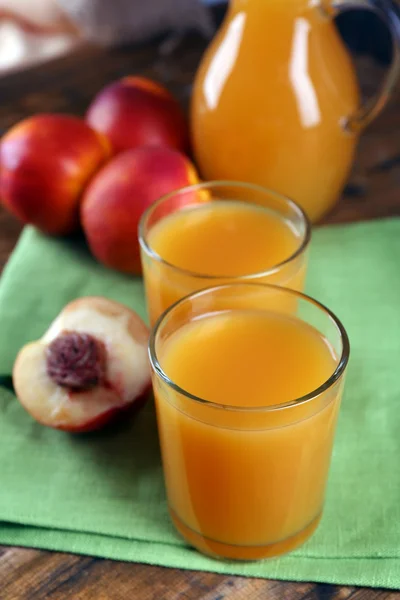 Peach juice and ripe peaches on wooden background — Stock Photo, Image