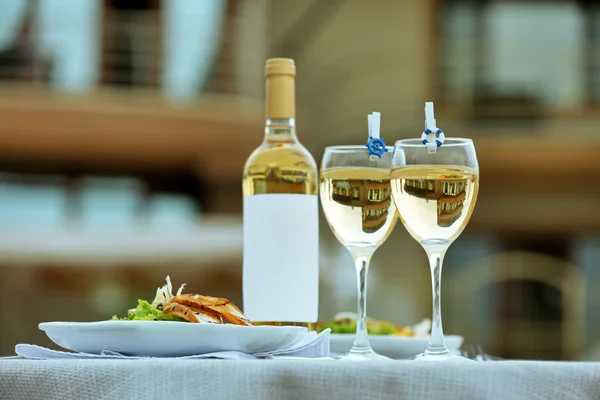 Botella de vino y dos copas llenas en mesa blanca —  Fotos de Stock