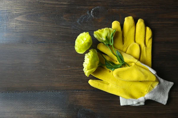 Gloves and flowers on wooden background — Stock Photo, Image