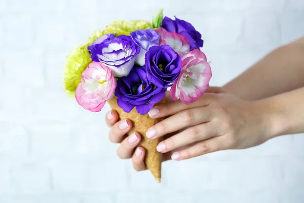 Kvinnans hand som håller vilda blommor i wafer — Stockfoto