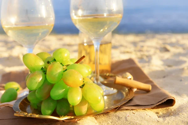 Composizione romantica di vino bianco e uva sulla spiaggia sabbiosa — Foto Stock