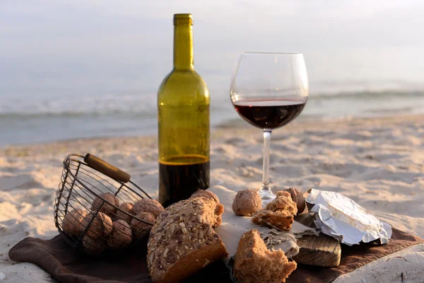 Nádherná romantická skladba červené víno, chléb a ořechy na písečné pláži — Stock fotografie