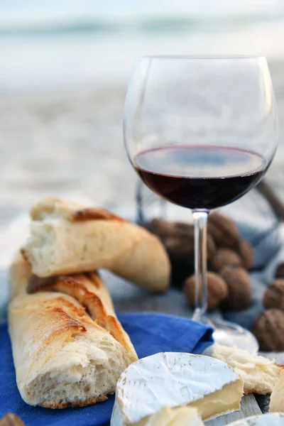 Hermosa composición romántica de vino tinto, pan y nueces en la playa de arena —  Fotos de Stock