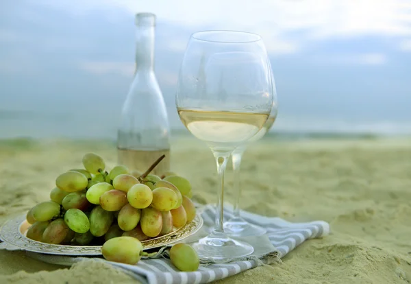 Composição romântica de vinho branco e uva na praia de areia — Fotografia de Stock