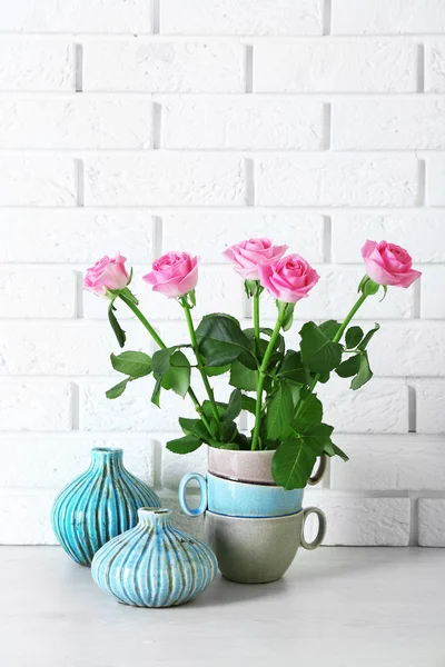 Schöne Rosen und Vasen auf Backsteinmauer Hintergrund — Stockfoto