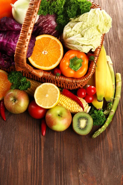 A set of fruit and vegetables in a basket on wooden background