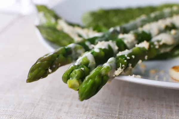 Prato de espargos delicioso com cebolas e molho verde na mesa, close-up — Fotografia de Stock