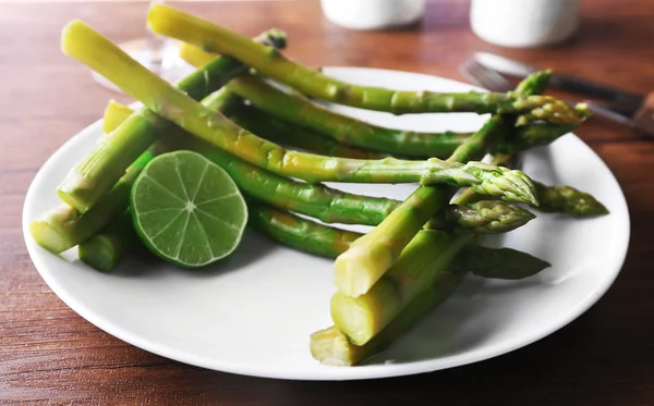 Piatto di asparagi freschi con calce su sfondo bianco, primo piano — Foto Stock