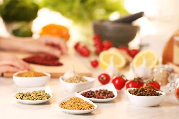 Variedade de especiarias em recipientes de cerâmica na mesa da cozinha — Fotografia de Stock