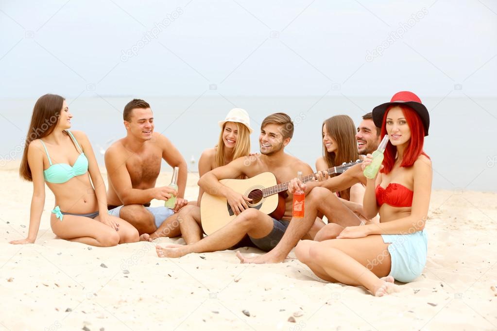 Beautiful young people with guitar on beach