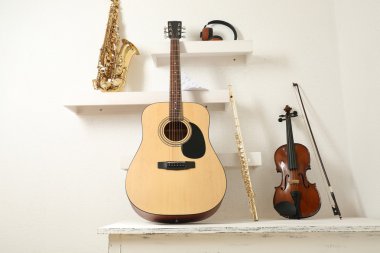 Müzik aletleri ve kulaklıklar beyaz duvar arka plan karşı bir şekilde dekore edilmiş raflar