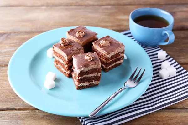 Söt chokladkaka på blå tallrik på träbord — Stockfoto