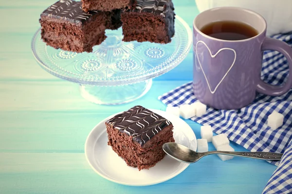 Tavola servita con una tazza di tè e torte al cioccolato su sfondo blu primo piano — Foto Stock
