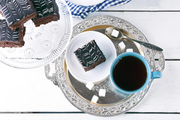 Mesa servida con pastel de chocolate y una taza de té sobre fondo de madera blanca — Foto de Stock