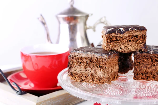 Mesa servida con pasteles de chocolate, una taza de té y tetera de cerca —  Fotos de Stock