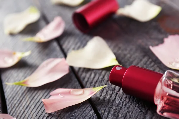 Botella de perfume y pétalos de rosa — Foto de Stock