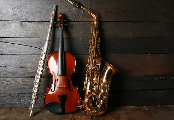 Instrumentos musicales: saxofón, violín y flauta sobre fondo de madera — Foto de Stock