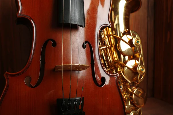 Vista de perto sobre instrumentos musicais: saxofone, violino em caixa de madeira — Fotografia de Stock