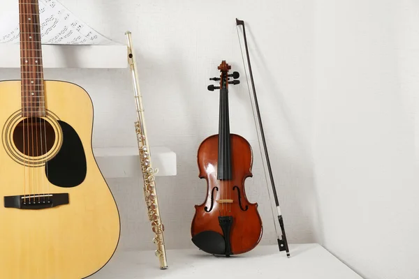 Instrumentos musicais em prateleiras decoradas contra fundo da parede branca — Fotografia de Stock