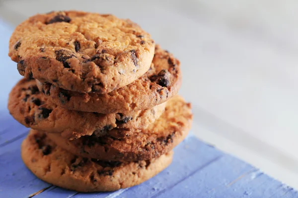 Cookie-k elmosódott háttér, kék fa tábla csokoládé morzsa közelről — Stock Fotó