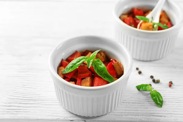 Ratatouille vegetariano saboroso feito de berinjelas, abóbora, tomates em tigelas em fundo de mesa de madeira — Fotografia de Stock